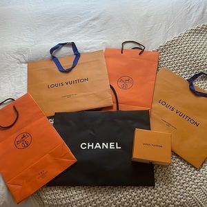 Various authentic luxury brand paper bags and an authentic box
